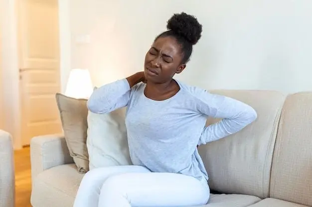 Young woman on a sofa holding her neck and lower back in pain